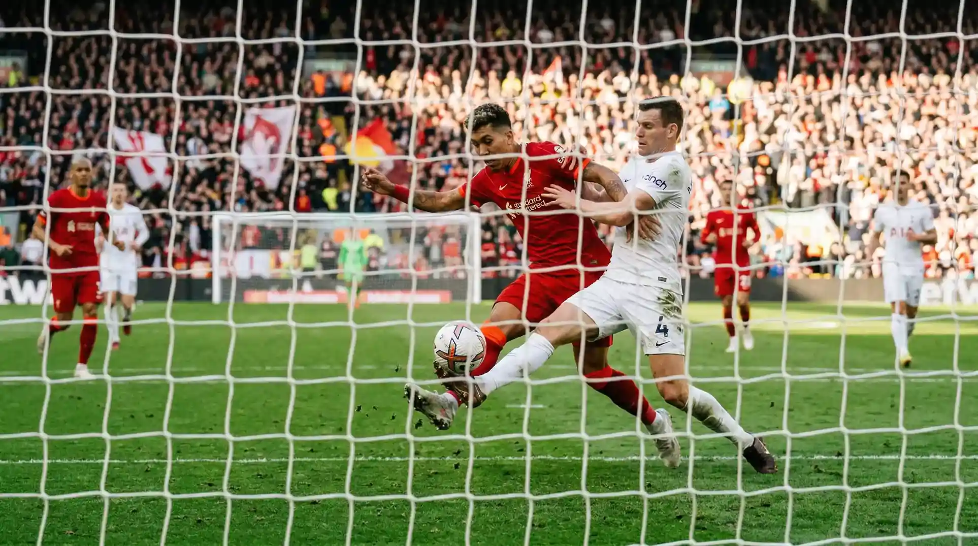 Fodboldspillere i aktion under en intens gruppekamp på en oplyst bane med fulde tribuner
